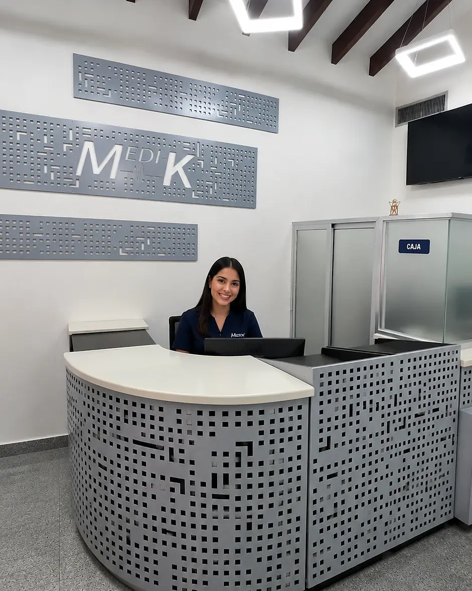 Recepcionista de Medik sonríe detrás del mostrador perforado de la sede